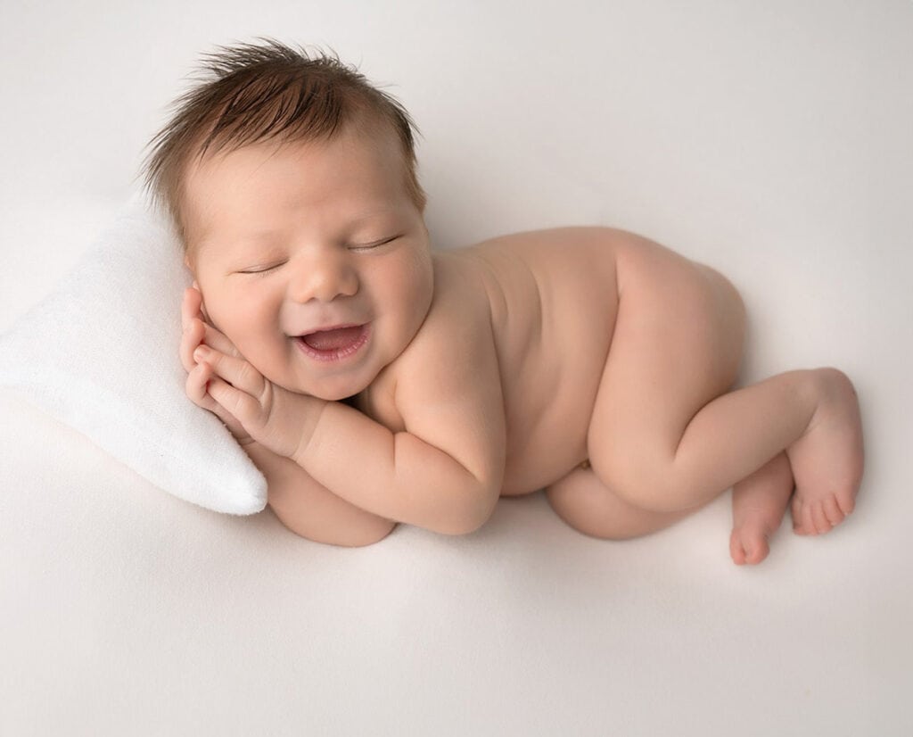 Cute newborn baby sleeping with a hug e smile. In-home newborn session in Philadelphia that looks like a studio.