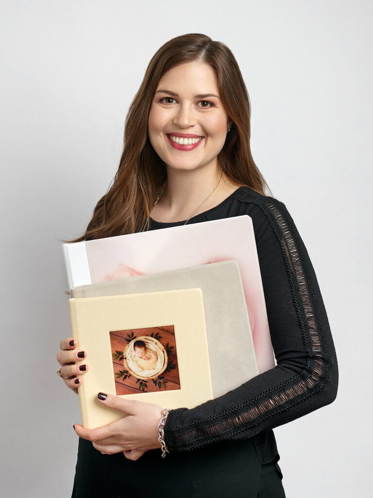 Jessica, holding 3 custom albums in her Philadelphia newborn studio.